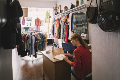 Woman working at desk while sitting in thrift store