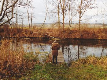 Rear view of a man standing on lakeshore