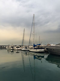 Sailboats moored at harbor against sky