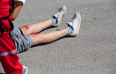 Low section of man with wounded leg on road