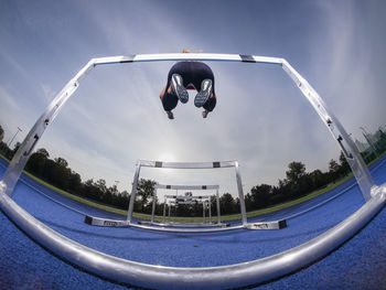 Athlete jumping over hurdle on track at training ground