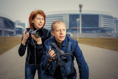 Portrait of young couple holding camera