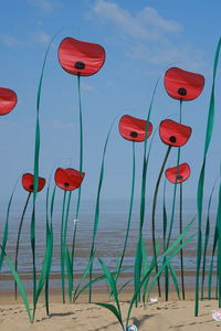 Red toy on beach against blue sky