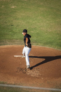 Teen baseball pitcher in black and white uniform on the mound