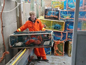 Full length of manual worker holding fishing net while working outdoors