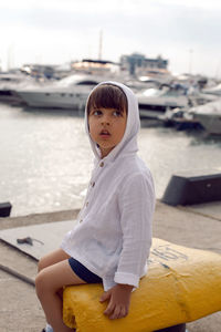 Boy child traveler sitting on the marina with yachts in sochi in the summer