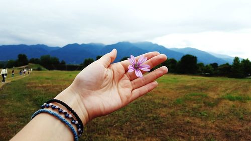 Midsection of person holding hand on grassy field