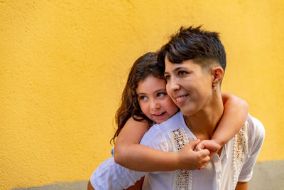 Portrait of a smiling young woman against yellow wall