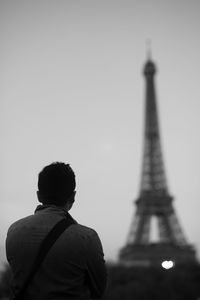 Rear view of man looking at eiffel tower against clear sky