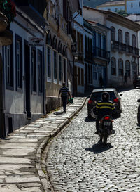 Rear view of man on street amidst buildings in city