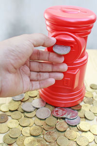 Cropped hand by piggy bank over coins on table