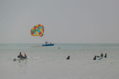 People enjoying on beach against clear sky