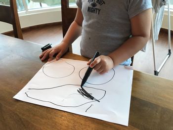 Midsection of boy drawing on paper