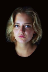 Portrait of young woman against black background