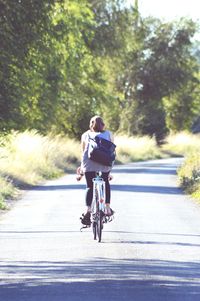 Rear view of woman riding bicycle on road