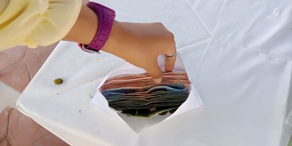 Cropped hand of person with money in envelope on table