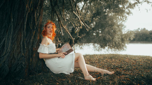 Full length of young woman sitting on field