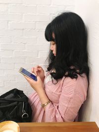 Young woman sitting against wall at home