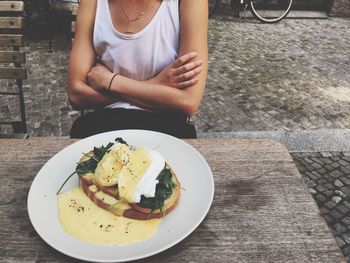 Midsection of woman with food on table at sidewalk cafe