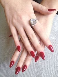 Cropped image of woman hands with red nail polish wearing heart shape ring