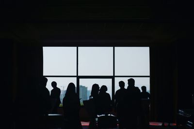 Silhouette of people standing in window