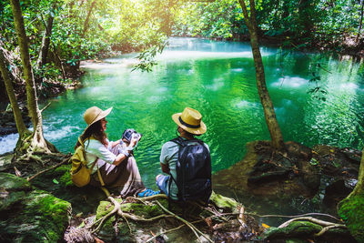 People sitting by lake in forest