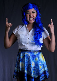 Portrait of smiling young woman standing against gray background