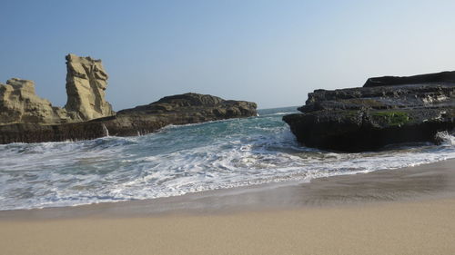 Rock formation on beach against clear sky