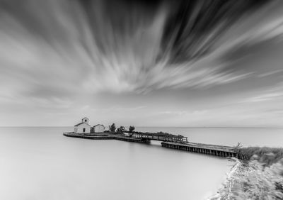 Pier over sea against cloudy sky