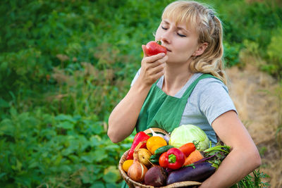 Smiling farmer holding tomato at farm