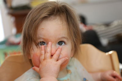 Close-up of cute baby girl with messy face looking away while sitting on chair at home