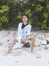 Portrait of smiling young woman sitting on land