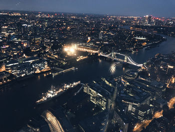 High angle view of illuminated buildings by river at night