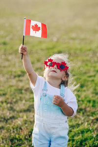 Cute girl holding canadian flag outdoors