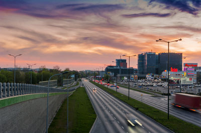 Vehicles on road against sky during sunset