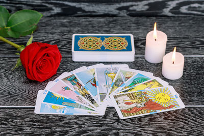 High angle view of tarot cards with candles and rose on table