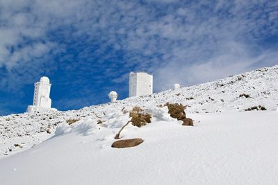 Snow covered land against blue sky