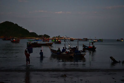 People on beach against sky at dusk