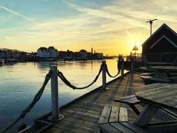 Pier over sea against buildings in city during sunset