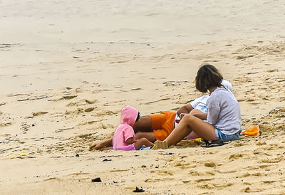 Rear view of girl sitting on beach