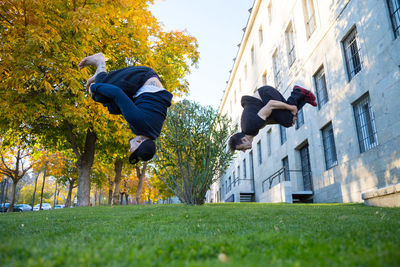 Low angle view of men jumping by building