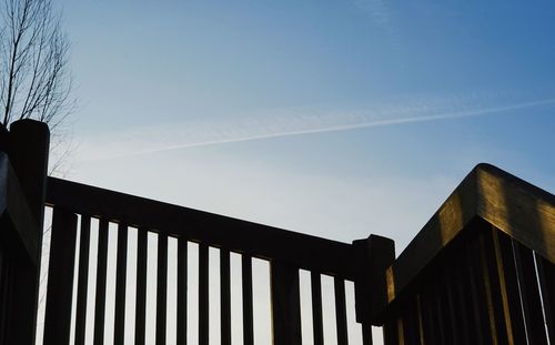 Low angle view of metal fence against blue sky