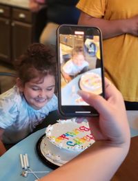 Midsection of woman photographing with smart phone on table