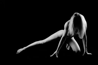 Woman with arms outstretched against black background