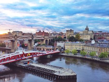Swing bridge over river tyne in city against cloudy sky