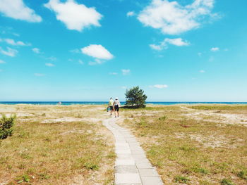 Rear view of couple walking on walkway against sky