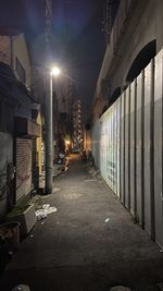 Empty road amidst buildings in city at night