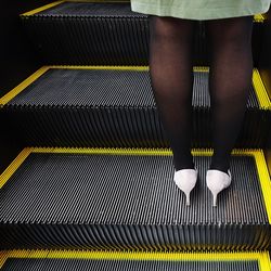 Low section of woman standing on escalator