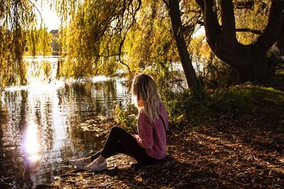 Side view of woman sitting by lake