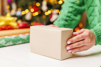 Cropped hand of woman holding gift box on table